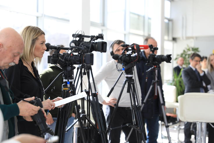 Television cameras lined up on tripods, capturing an event.