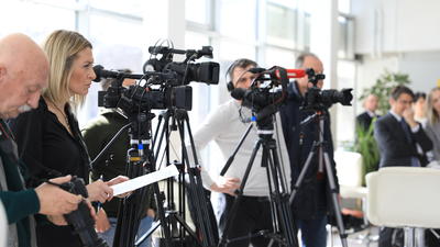 Television cameras lined up on tripods, capturing an event.