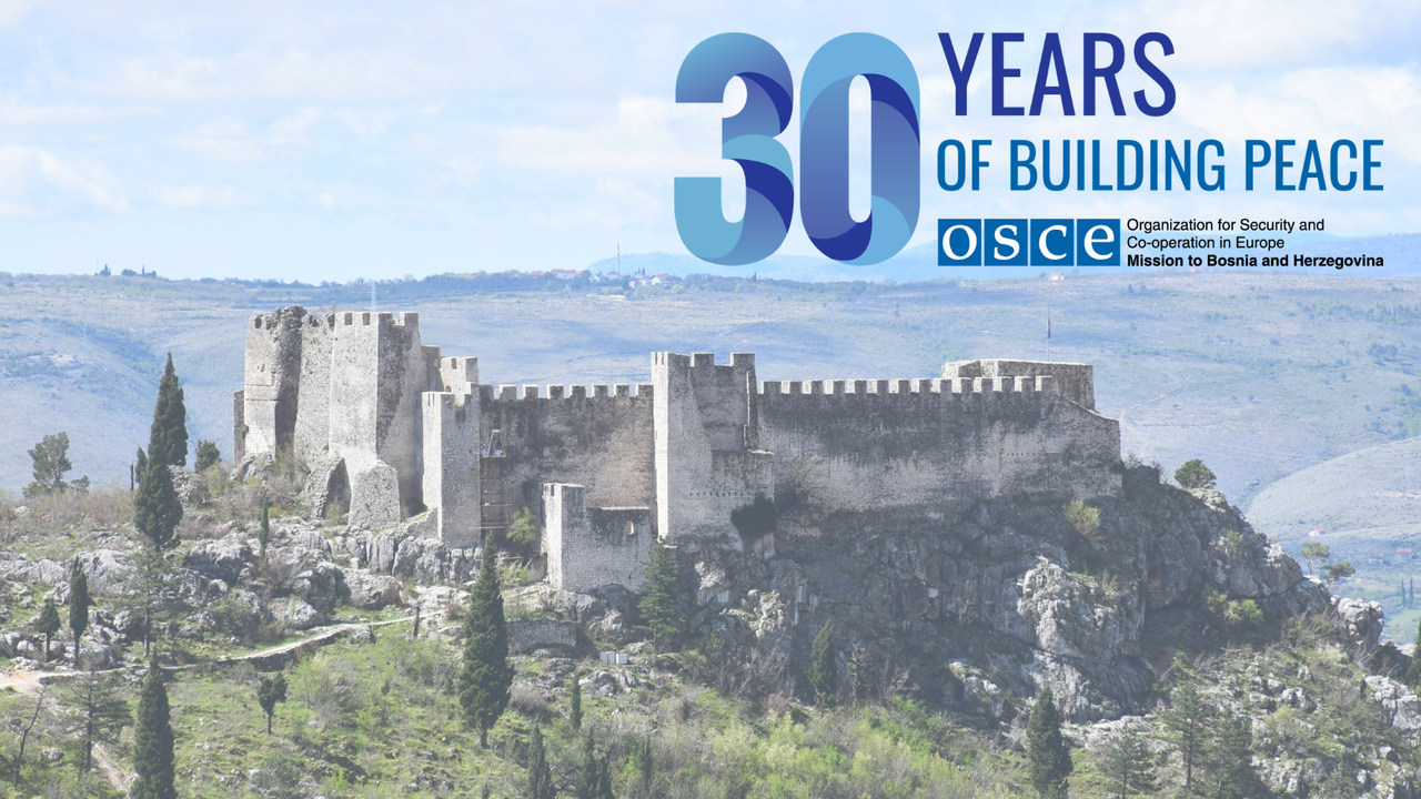 A historic stone castle on a hill surrounded by greenery under a blue sky, with text celebrating 30 years of peace.
